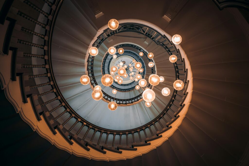 Elegant spiral staircase in London with a stunning chandelier, creating a mesmerizing visual effect.