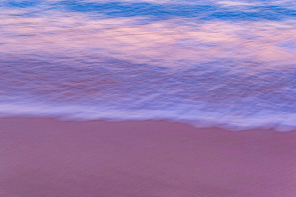 Gentle ocean waves on a serene beach at sunset creating a peaceful and calming atmosphere.