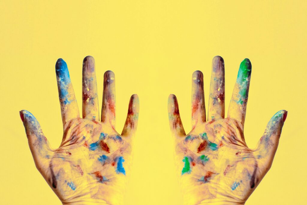 Colorful fingers spread against a bright yellow backdrop, showcasing creativity.